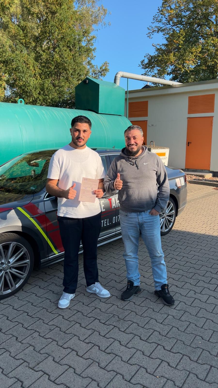 Erfolgreicher Fahrschüler vor dem Passat